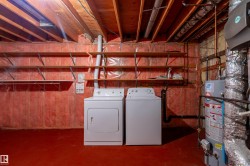 Utility area featuring a water heater, exposed wood joists, and a concrete floor - 