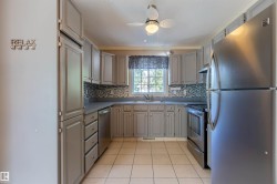 Kitchen featuring gray shaker-style cabinetry, solid surface countertops, and a mosaic tile backsplash - 