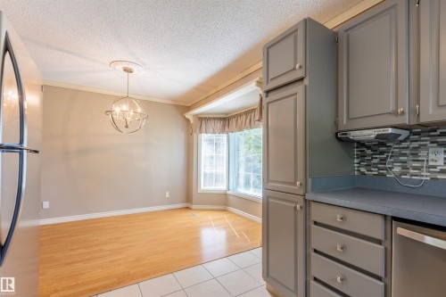 Kitchen cabinetry featuring gray shaker-style doors, a mosaic tile backsplash, and a built-in dishwasher - 3 Glenforest Crescent, Stony Plain, AB 