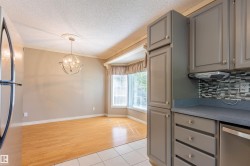 Kitchen cabinetry featuring gray shaker-style doors, a mosaic tile backsplash, and a built-in dishwasher - 