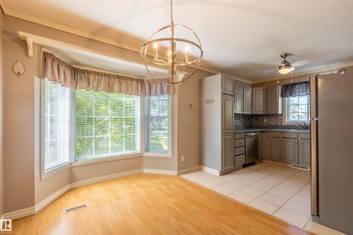 Integrated kitchen and dining area featuring a bay window, wood-finish flooring, tile flooring, updated cabinetry, and a ceiling fan - 3 Glenforest Crescent, Stony Plain, AB 