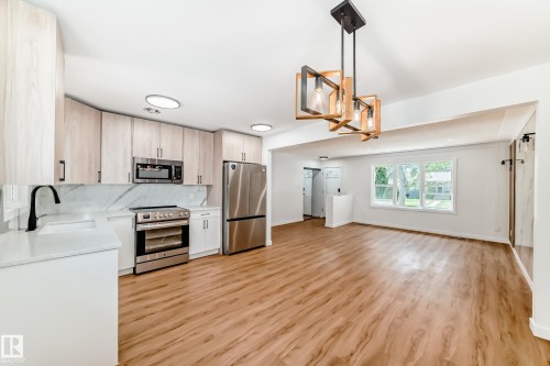 Modern kitchen featuring light wood-finish cabinetry, stainless steel appliances, white countertops, and a white marble-look backsplash - 4842 116Ave, Edmonton, AB - Indoor Photo Showing Kitchen