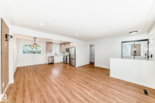 Open concept living area featuring wood-finish flooring, recessed lighting, and a modern kitchen with stainless steel appliances - 4842 116Ave, Edmonton, AB - Indoor