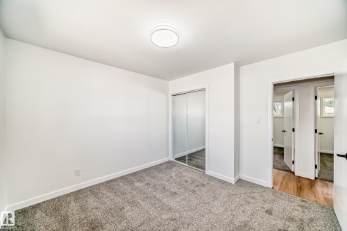 Carpeted interior room featuring a contemporary ceiling light fixture, white walls, and white baseboards - 4842 116Ave, Edmonton, AB - Indoor Photo Showing Other Room