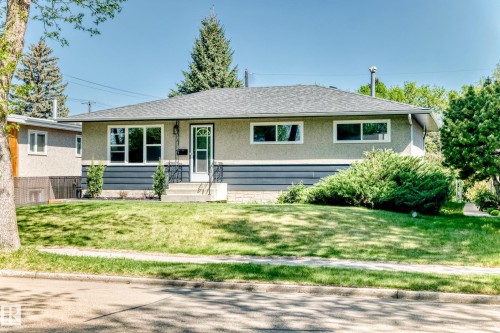Ranch-style residence featuring a gray shingle roof, stucco exterior with dark gray horizontal siding accents, and white-framed windows - 4842 116Ave, Edmonton, AB - Outdoor
