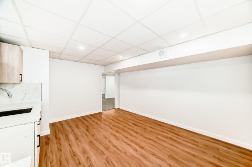 Open-concept living space featuring wood-finish flooring, white walls, and a drop ceiling with recessed lighting - 4842 116Ave, Edmonton, AB - Indoor Photo Showing Other Room