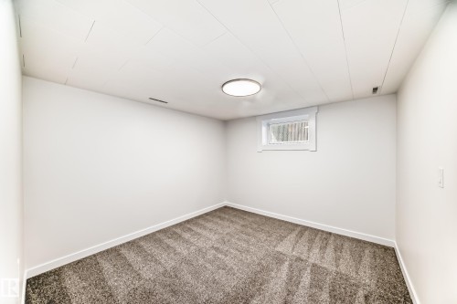 Carpeted room featuring white walls, a single window with white trim, a flush-mount ceiling light fixture, and a white paneled ceiling - 4842 116Ave, Edmonton, AB - Indoor Photo Showing Other Room