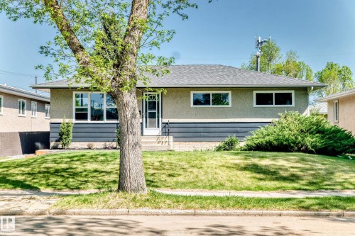 Stucco exterior with horizontal dark siding accent and a gray shingle roof - 4842 116Ave, Edmonton, AB - Outdoor