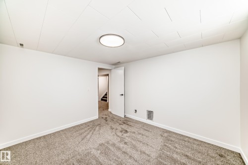 Carpeted room featuring white walls, white trim, and a white ceiling with an integrated flush-mount circular light fixture - 4842 116Ave, Edmonton, AB - Indoor Photo Showing Other Room