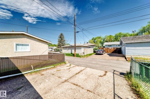 Property exterior featuring stucco siding, a white-framed window, and a brown privacy fence - 4842 116Ave, Edmonton, AB - Outdoor