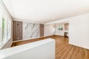 Open-concept living area featuring wood-finish flooring, recessed lighting, and a decorative accent wall with a marble-effect panel and vertical wood slat details - 4842 116Ave, Edmonton, AB  - Indoor Photo Showing Other Room 