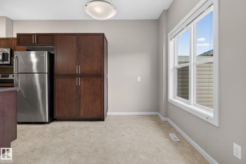 Kitchen dining area featuring a prominent window, neutral wall color, and light-toned flooring - 57 3710 Allan Drive, Edmonton, AB 