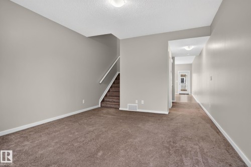 Open concept room featuring neutral tone walls and brown carpeting - 57 3710 Allan Drive, Edmonton, AB 