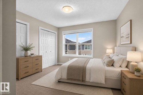 Bedroom featuring neutral wall paint, carpet flooring, a window with white trim, and a ceiling-mounted light fixture - 57 3710 Allan Drive, Edmonton, AB 