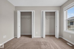 Carpeted room with two bi-fold door closets, neutral wall paint, and a single window with white trim - 