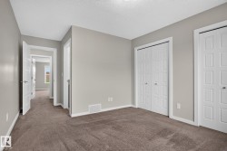 Neutral-toned interior room with plush carpet flooring, multiple bi-fold closet doors, and white trim - 