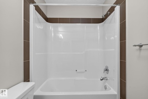White bathtub/shower combination with a single handle shower faucet and a curved shower rod - 57 3710 Allan Drive, Edmonton, AB 