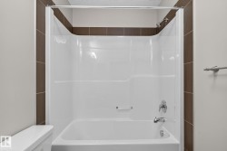White bathtub/shower combination with a single handle shower faucet and a curved shower rod - 