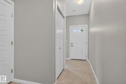 Bright interior hallway featuring light gray walls and beige carpeting - 