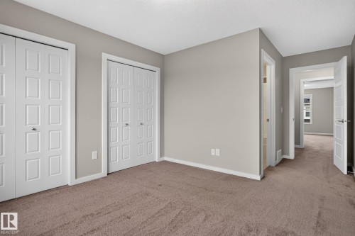 Spacious room with plush brown carpeting and light gray wall paint - 57 3710 Allan Drive, Edmonton, AB 