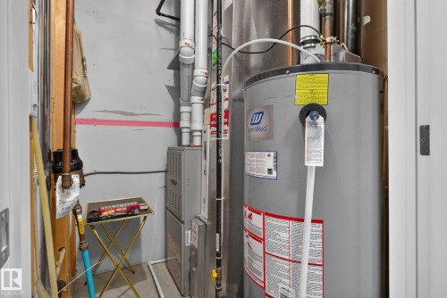 Utility closet featuring a water heater, furnace, and exposed copper piping - 57 3710 Allan Drive, Edmonton, AB 