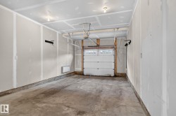 Single-bay garage with concrete flooring and unfinished drywall walls - 