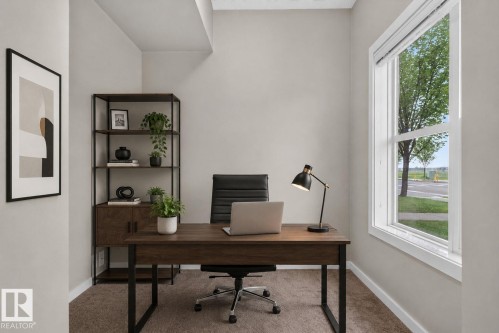 Dedicated office space featuring a large window, neutral wall paint, and carpeted flooring - 57 3710 Allan Drive, Edmonton, AB 