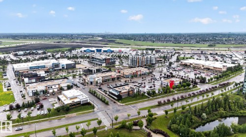 Aerial perspective of a commercial district featuring multiple retail establishments, extensive parking areas, and mature landscaping - 57 3710 Allan Drive, Edmonton, AB 