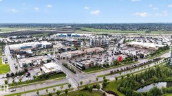 Aerial perspective of a commercial district featuring multiple retail establishments, extensive parking areas, and mature landscaping - 