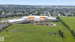 Expansive green field featuring soccer goals with a modern building and playground structures in the background - 