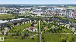 Aerial perspective highlighting residential properties bordering a central green space with walking paths and two distinct playground areas - 