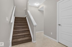 Carpeted staircase with white trim and handrails, complemented by a contemporary five-panel interior door - 