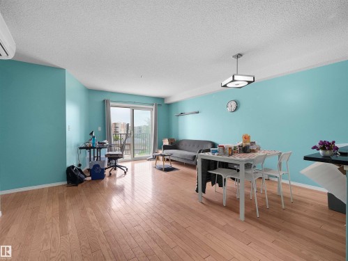 Expansive living area with wood-finish flooring and direct access to a private balcony - 313 11820 22 Avenue, Edmonton, AB 