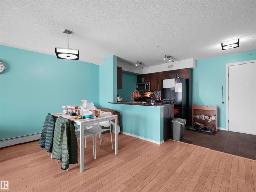Open concept living space featuring wood-finish flooring in the main area and contrasting tile flooring near the entry - 313 11820 22 Avenue, Edmonton, AB 