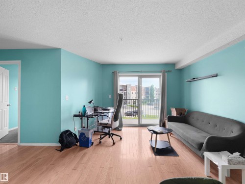 Spacious interior featuring wood-finish flooring, light blue walls, and a white ceiling - 313 11820 22 Avenue, Edmonton, AB 