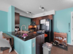 Kitchen featuring dark wood cabinetry, a built-in microwave, and a black refrigerator - 