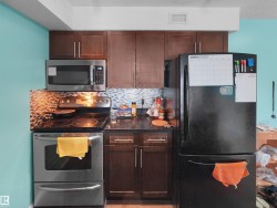 Kitchen featuring stainless steel appliances, dark wood-finish cabinetry, and a patterned tile backsplash - 