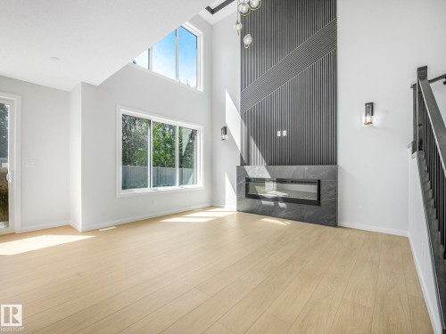 Spacious room featuring a contemporary linear fireplace with a dark stone-finish surround - 1717 Crossbill Loop, Edmonton, AB - Indoor With Fireplace