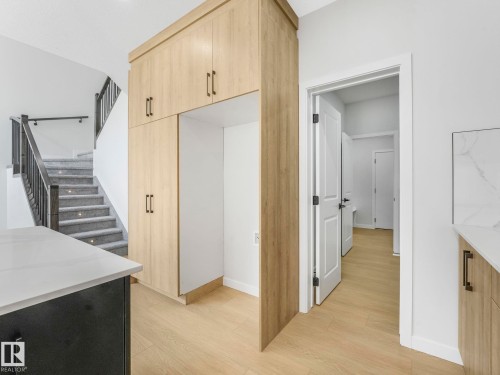 Built-in wood-finish cabinetry featuring black hardware, an open refrigerator cavity, and recessed lighting - 1717 Crossbill Loop, Edmonton, AB - Indoor Photo Showing Other Room