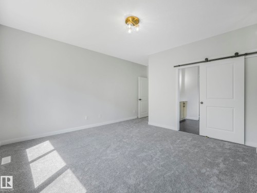 Spacious room featuring light gray carpeting, neutral wall paint, and a brass flush-mount ceiling light - 1717 Crossbill Loop, Edmonton, AB - Indoor Photo Showing Other Room