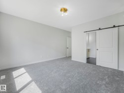 Spacious room featuring light gray carpeting, neutral wall paint, and a brass flush-mount ceiling light - 