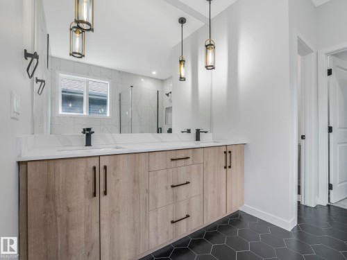 Double vanity with a light wood-finish cabinet, white countertop, and matte black fixtures - 1717 Crossbill Loop, Edmonton, AB - Indoor Photo Showing Bathroom