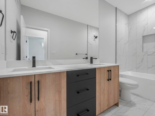 Dual vanity featuring wood-finish cabinetry, matte black hardware, and integrated sinks with single-handle faucets - 1717 Crossbill Loop, Edmonton, AB - Indoor Photo Showing Bathroom
