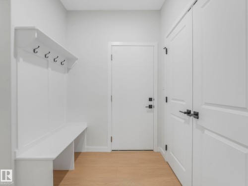 Built-in white storage bench with upper shelf and coat hooks - 1717 Crossbill Loop, Edmonton, AB - Indoor Photo Showing Other Room