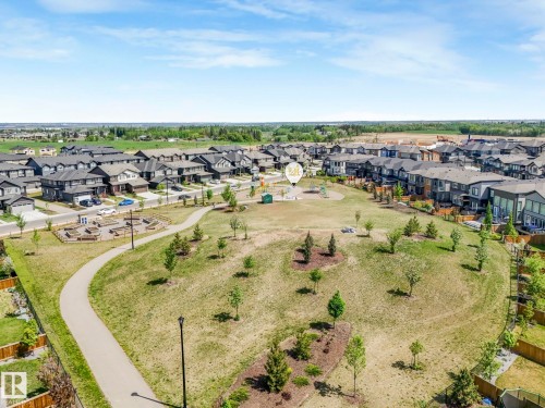 Expansive greenspace featuring a paved walking path, scattered trees, and a central play area - 1717 Crossbill Loop, Edmonton, AB - Outdoor With View