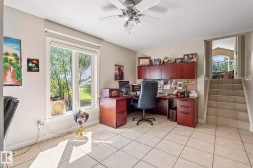 Spacious room featuring light-toned tile flooring, a large window offering exterior views, and a ceiling fan with integrated lighting - 860 41 Avenue, Edmonton, AB 
