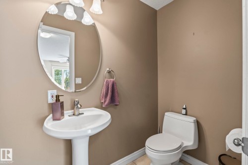 Pedestal sink with a polished chrome faucet, oval mirror, and a three-light vanity fixture - 860 41 Avenue, Edmonton, AB 