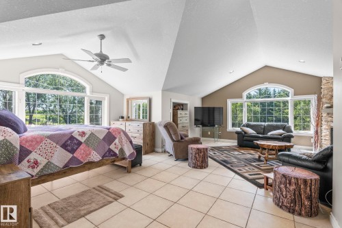 Spacious room featuring vaulted ceilings, large arched windows, tile flooring, and a stone-clad fireplace - 860 41 Avenue, Edmonton, AB 