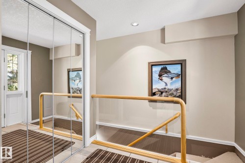 Mirrored closet doors providing visual expansion, alongside a glass panel and wood handrail staircase - 860 41 Avenue, Edmonton, AB 