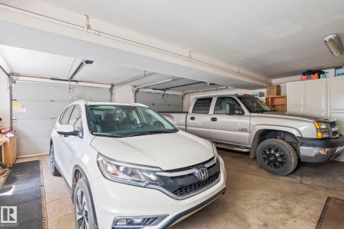 Spacious two-car garage featuring two overhead garage doors, concrete flooring, and built-in storage cabinetry - 860 41 Avenue, Edmonton, AB 